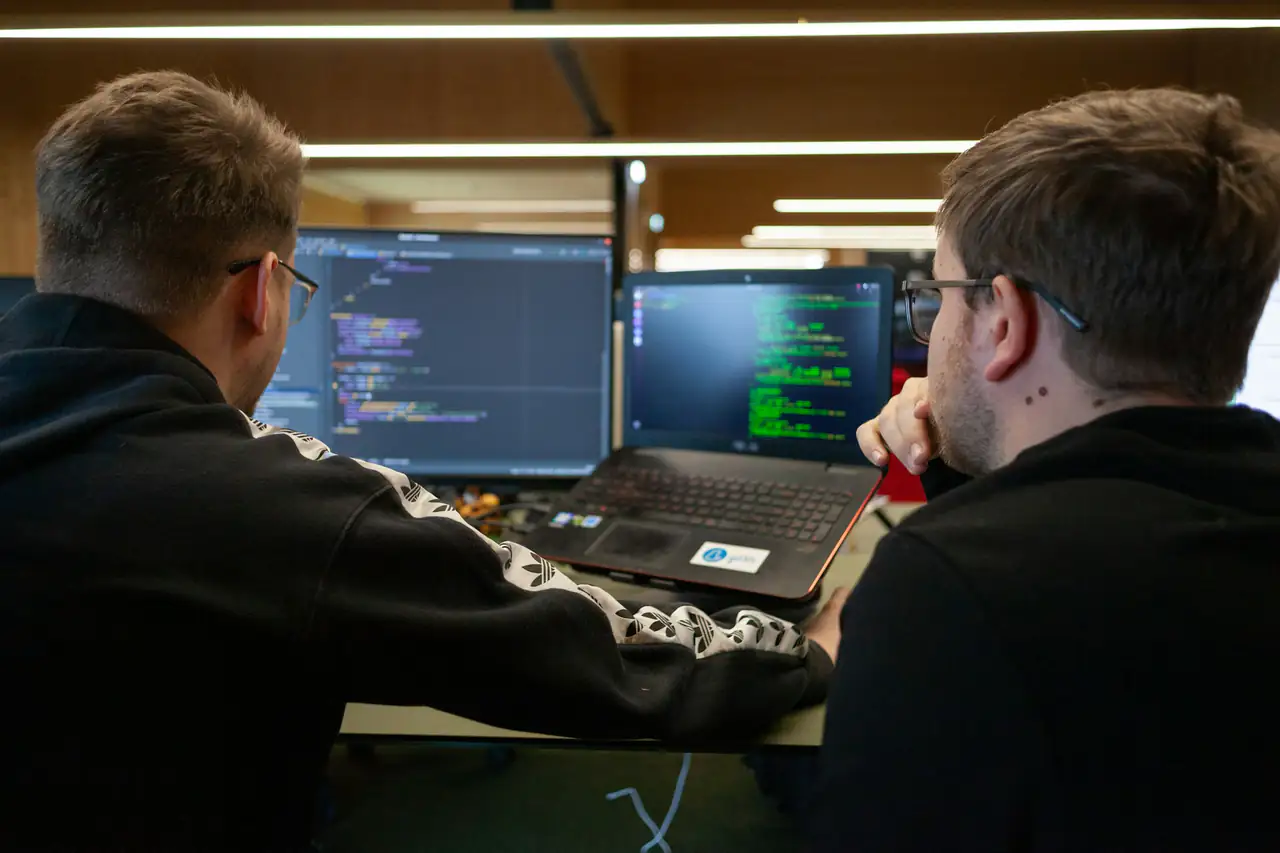 Two engineers working side by side at their monitors