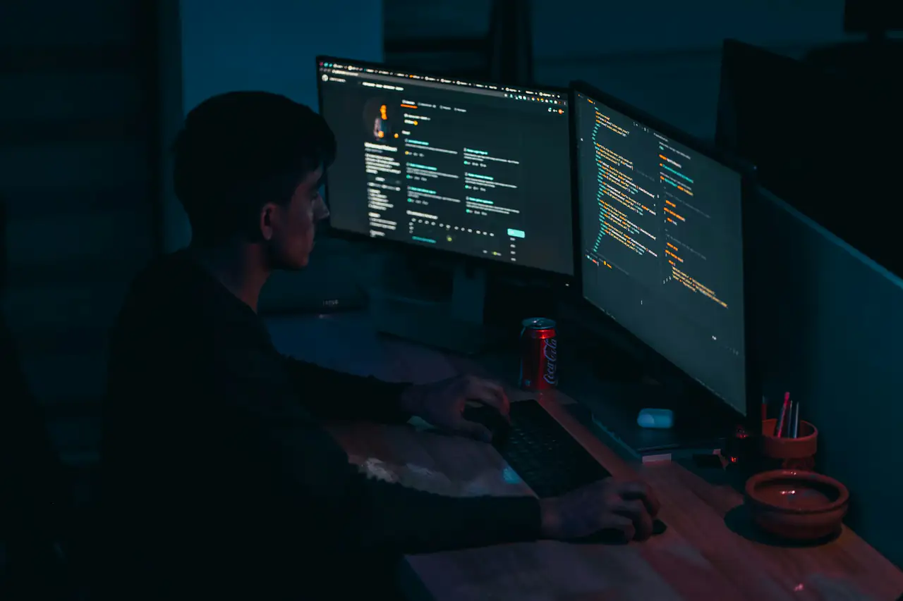 An engineer reviewing code across two monitors in a dark studio